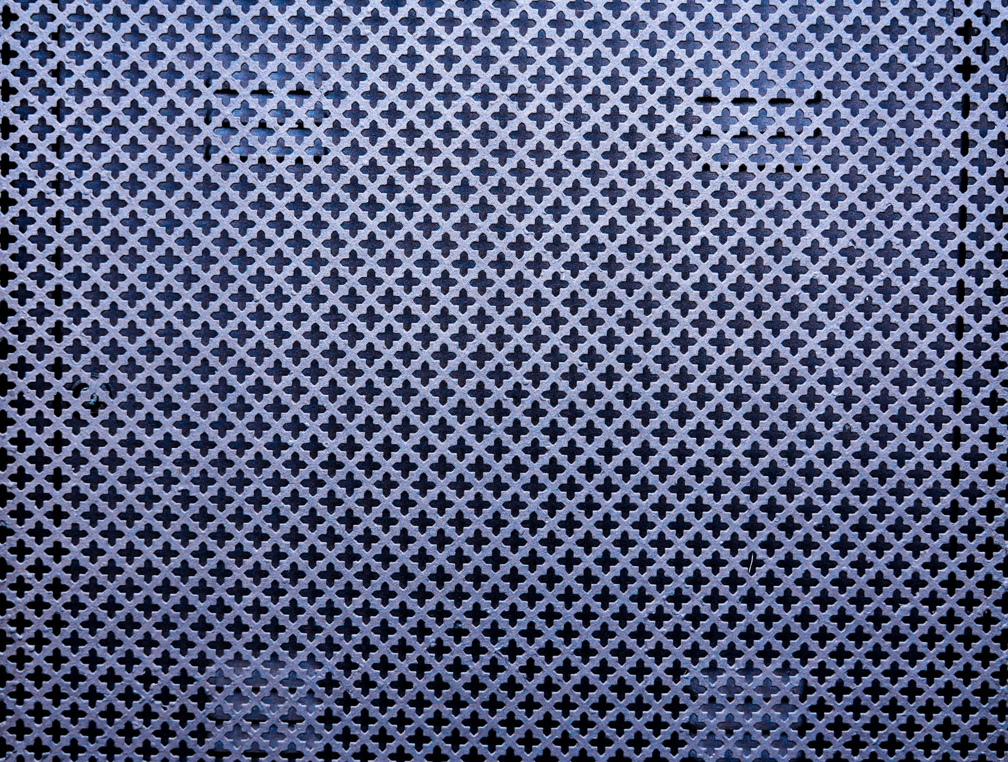 Close-up of a metal wall with intricate patterns and shapes, creating a textured abstract design.