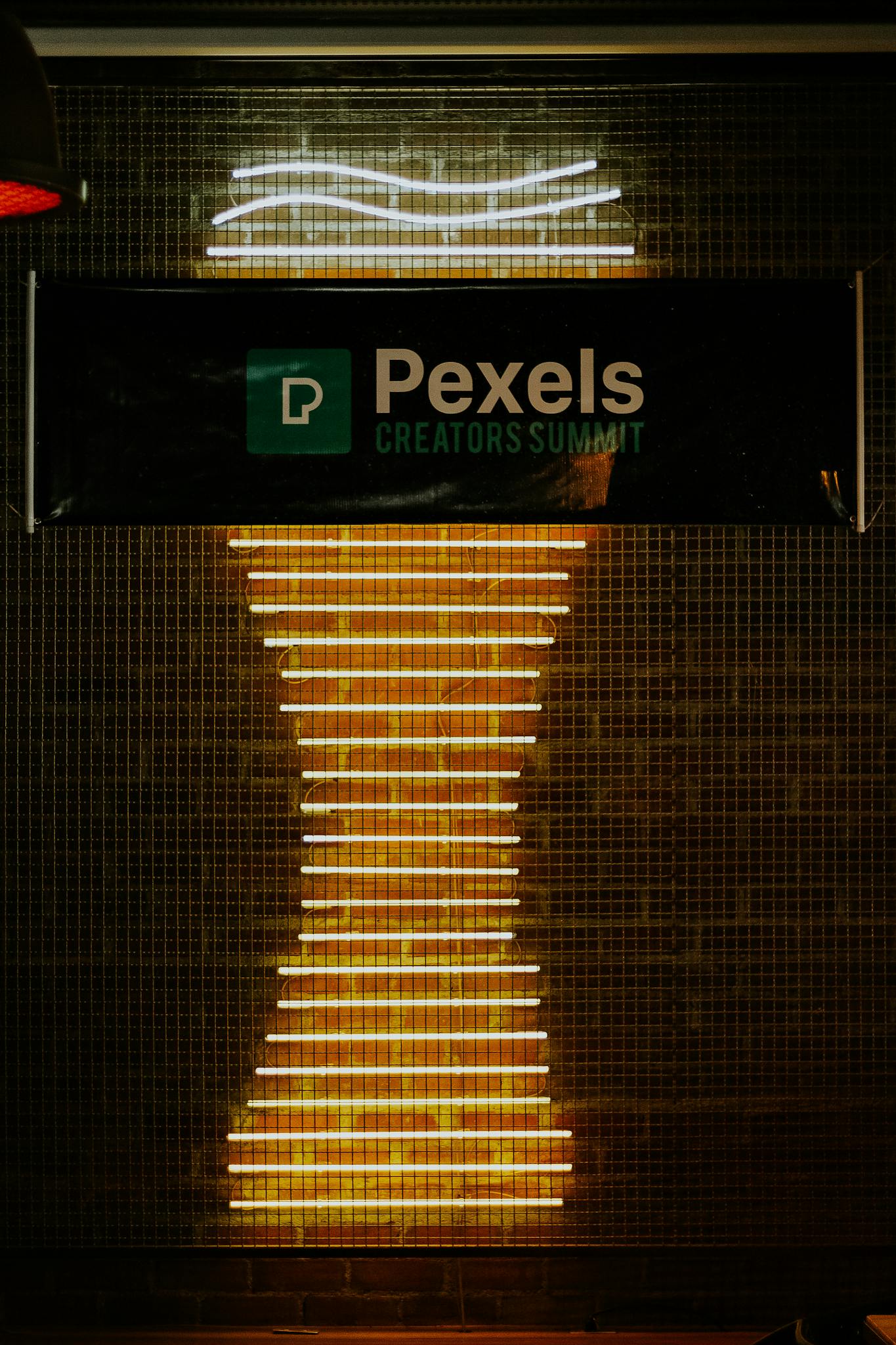 Illuminated neon sign display at Pexels Creators Summit with abstract design.