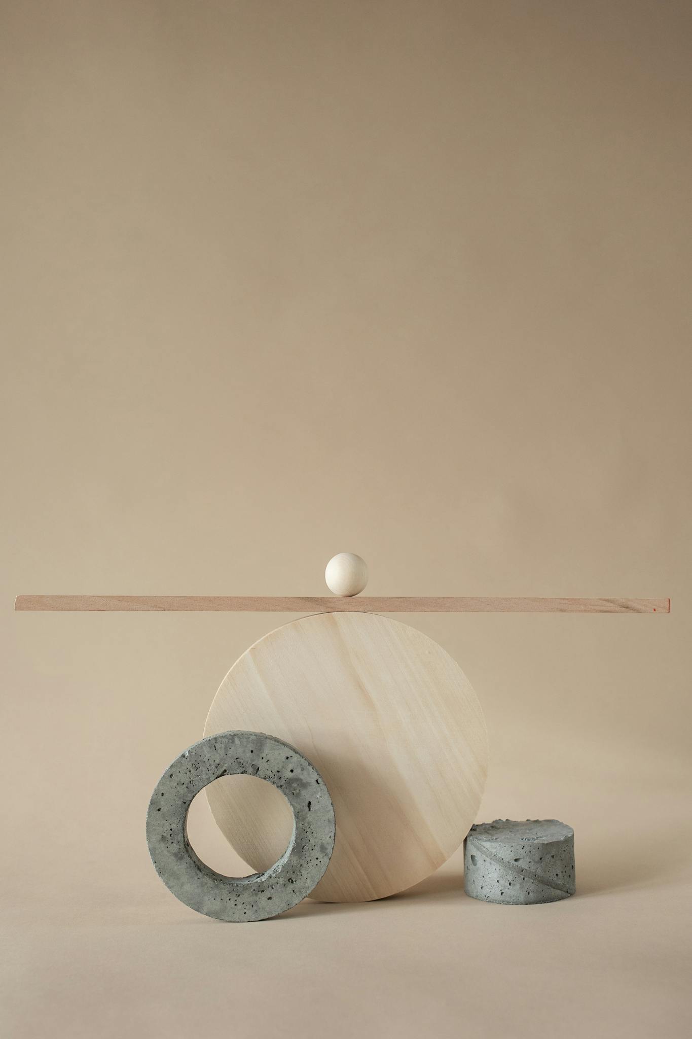 Modern abstract geometric sculpture with spheres and cylinders on a beige background, showcasing minimalist art.